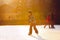 Children, playing hockey and skating in the park on frozen lake, wintertime on sunset