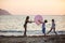 Children playing with huge pink balloon on beach