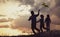 Children playing with kite on summer sunset meadow silhouetted