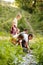 Children playing near little river in forest, wetting hands, taking stones Warm sunny day activity. Exploring nature