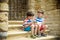 The children playing on the ruins of ancient building with metal gate an archaeological site of an ancient city. Two boys sitting