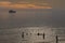 Children playing in the sea as a boat goes past