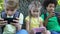 Children playing smartphone games sitting under tree in park, gadget addiction