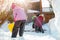 Children playing together in yard after snowfall in winter. Group of kids bilding figures and snowman with shovels and other tools