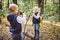 Children preschoolers Caucasian brother and sister take pictures of each other on mobile phone camera in forest park