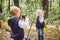 Children preschoolers Caucasian brother and sister take pictures of each other on mobile phone camera in forest park