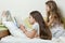 Children are reading a book lying in bed at home. The elder girl reads aloud to the younger sister