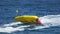 Children riding banana boat, speed floating, summer water attraction in slow-mo