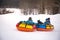 children are rolling down snow tubing