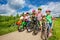 Children in row wearing helmets holding bikes