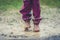 Children in rubber boots and rain clothes jumping in puddle.