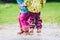 Children in rubber boots and rain clothes jumping in puddle.