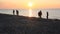 Children run on the beach in the rays of the setting sun.