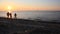 Children run on the beach in the rays of the setting sun.