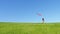 Children run down the green hill with a flying kite