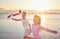 Children running with airplane toys on beach together for wellness, exercise and healthy development on sunset horizon