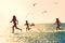 Children running along the sea at sunset