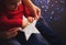 Children`s and adult hands holding Glowing white LED star with garland bokeh background indoor at home.