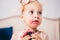 Children`s birthday. funny two-year-old Caucasian girl in pink dress standing to bedroom of house the background of couch and eat