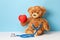 Children's doctor or family doctor. Teddy bear with a stethoscope is holding red heart