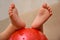 Children`s feet on the ball. Baby feet on the ball. Small baby feet