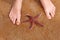 Children\'s feet with a beautiful starfish on the beach.
