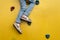 Children`s feet in blue jeans close-up on a yellow climbing wall.
