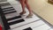 Children's feet play on the huge piano keys on the floor of the shopping center.