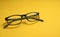 Children`s glasses lie on a yellow close-up with space for text. Copy Space. The concept of children`s myopia, astigmatism, visi