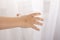 Children`s hand with a gold tattoo is touching the curtain. Light, airy curtain, bright gentle light.