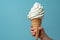 Children& x27;s hand holds delicious vanilla ice cream cone on a bluebackground with copy space