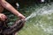 Children`s hand plays in the fountain in the yard. Water splashing from the fountain. Summer sunny day.