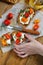 Children`s hands hold a bruschetta with ricotta cheese and sun-dried tomatoes with Provencal herbs.