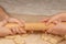 Children& x27;s hands hold a rolling pin against the background of dough on baking paper