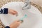 Children`s hands holding dental plate and toothbrush above the bathroom sink.