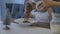 Children`s hands pour milk from a glass jug into a white plate, close-up