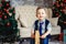 Children's joyful memories of Christmas holidays. Sweet stylish boy in a tie riding wooden rocking horse. Happy stylish