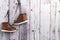 Children\\\'s leather demi-season boots hang on a gray wooden wall. Space for text