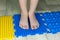 Children`s legs go on a multi-colored massage orthopedic rug against a colored floor