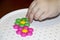 Children`s mosaic. the child lays a flower out of a colored plastic mosaic. the child`s hand holds a bright plastic mosaic piece