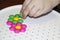 Children`s mosaic. the child lays a flower out of a colored plastic mosaic. the child`s hand holds a bright plastic mosaic piece