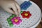 Children`s mosaic. the child lays a flower out of a colored plastic mosaic. the child`s hand holds a bright plastic mosaic piece