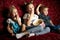 Children`s movies: Three children watch movies at home on a big red sofa in the dark and eat popcorn.