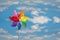 Children`s multi-colored toy wind propeller on a background of summer blue sky with clouds