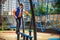 Children\\\'s obstacle course on a modern playground. Kid crossing a wooden bridge or other barriers using his body balance.