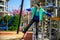 Children\\\'s obstacle course on a modern playground. Kid crossing a wooden bridge or other barriers using his body balance.