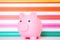 Children's Piggy Bank to encourage kids savings on a multi coloured, rainbow background with copy space