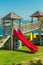 Children`s playground on the beach. Red hill and wooden houses for children on green grass