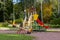 Children`s Playground in the Park against the background of autumn trees on a bright fine day. Multi-colored slide, swing and