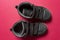 Children`s shoes made of black leather on a pink background.